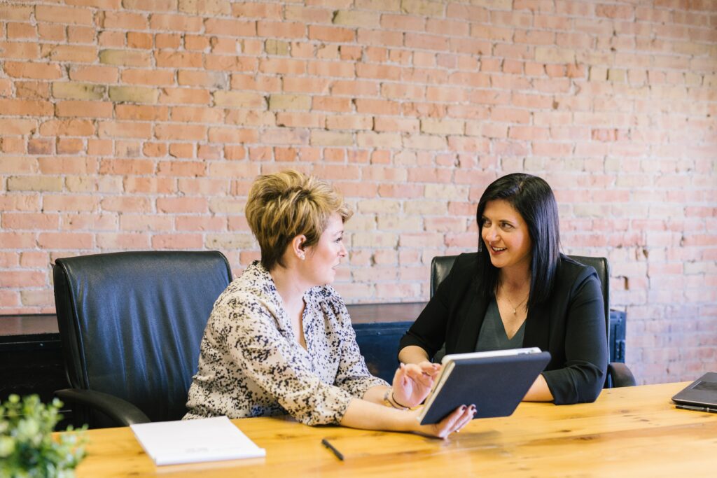 Two women sitting in a meeting room busy with desk work | Sage and Smart Pension team up to help automate pensions for SMEs