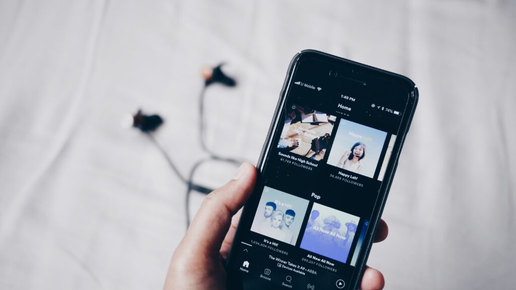 a hand holding a smartphone with the Spotify app open