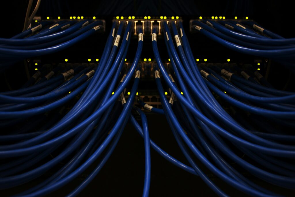A darkened close up of a server with symmetrical blue cabling and faint lights | Spinnaker Support